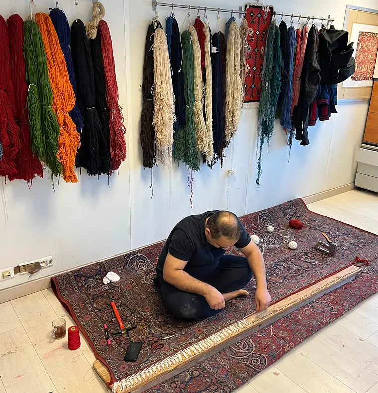 Atelier de restauration de tapis avec les écheveaux de laine teinte suspendus au mur