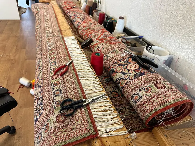 Établi d'atelier avec un tapis d'Orient, ses bobines de fil et ses ciseaux de tapissier