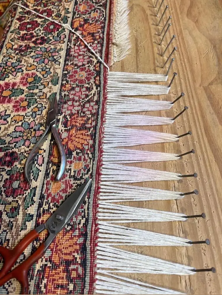 Rangée de franges neuves en coton peigné posées sur la tête d'un tapis persan