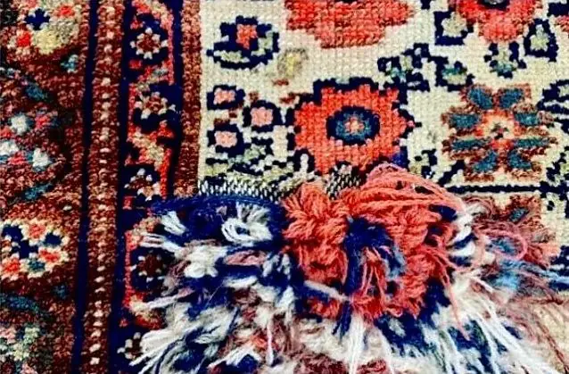Laines rouges et bleues nouées une à une pour reconstituer le motif d'un tapis