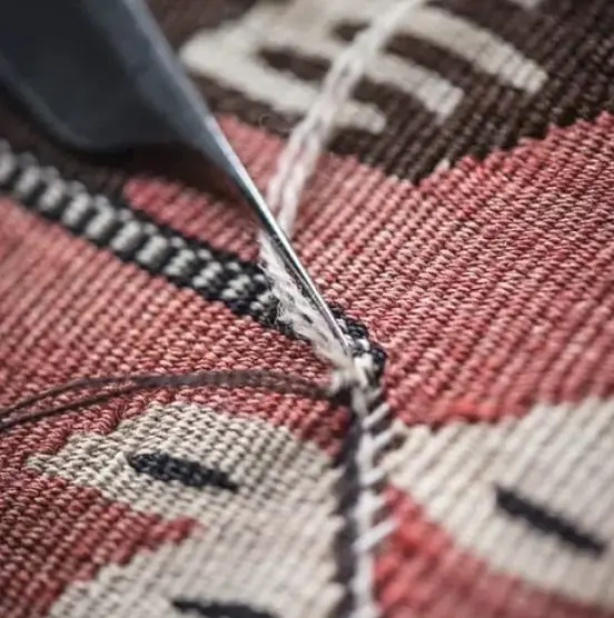 Outil fin réinsérant une duite colorée dans le tissage d'un kilim ancien